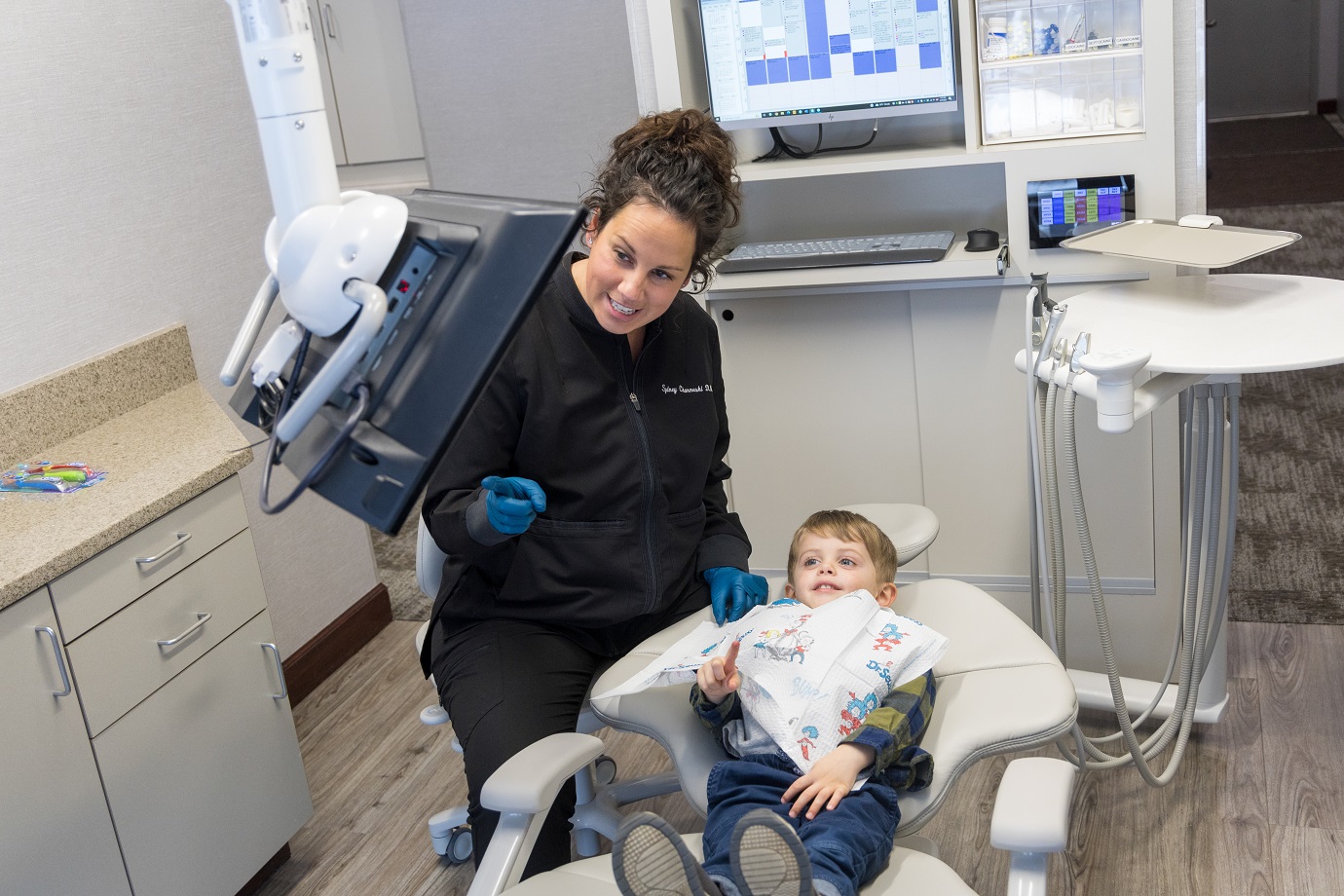 A dentist is showing something on the screen to her child patient
