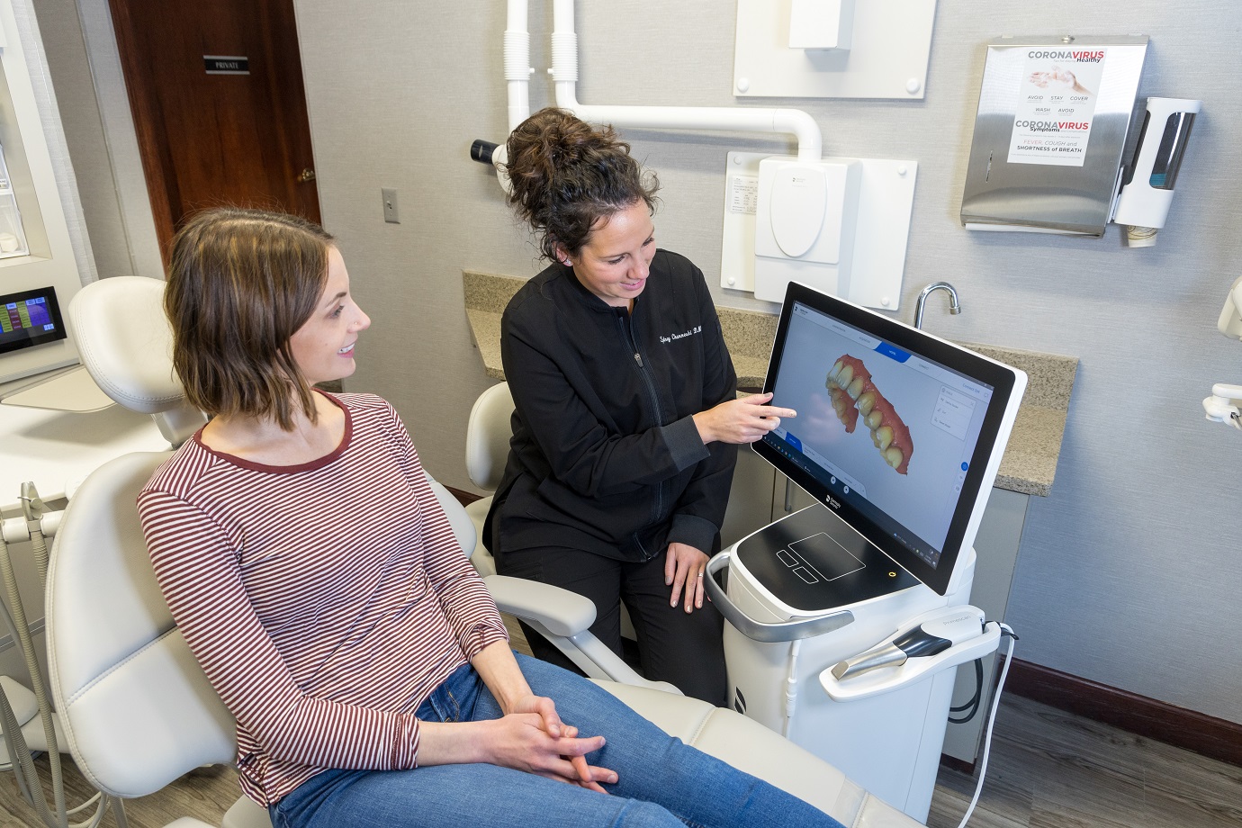 A dentist is showing something on the screen to her patient